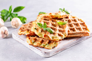 Zucchini waffle, zucchini fritters cooking on waffle maker, vegetarian zucchini waffles with basil and garlic on a white board