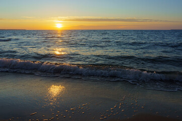 Naklejka premium Sunset over the sea. Reflection of sunlight in the sea waves. The sky in the sunset rays. Russia Baltic Sea.