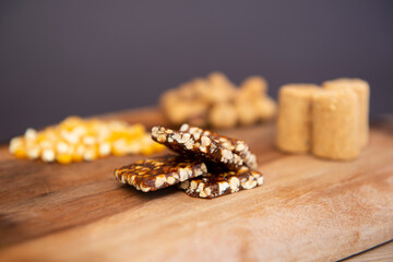 Typical brazilian June Party (Festa Junina) foods on a wooden table: peanuts candies (paçoca and pe-de-moleque) corn kernels, peanut pods. Copy space. Selective focus.