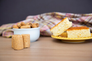 Typical June Party foods on a wooden table: cornmeal cake, peanut pods, peanuts candy (paçoca) and dulce de leche. Copy space. Selective Focus.