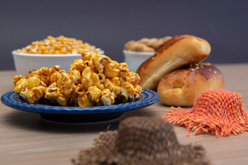 Close up of typical June Party foods on a wooden table: Popcorn, cornmeal cake, corn kernels, peanut pods and small country hats. Copy space. Selective focus.