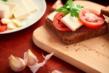 healthy food - fresh bread and feta cheese on a wooden background, tomatoes, greens and vegetables