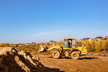 large yellow wheel loader aligns a piece of land for a new building. Preparation of the land for the auction. Leveling the landscape and adding sand for construction.
