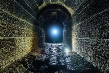 Dark and creepy old historical vaulted flooded underground drainage tunnel