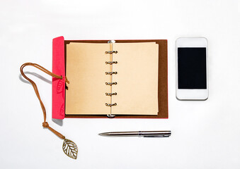 notebook with pen and phone, on a white background, shot from above