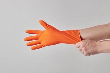 cleaning service concept. cleaner person wearing orange or yellow colored protective gloves. grey background. copy space.