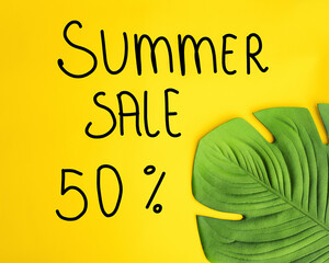 Photo of a Green leaf on a yellow background and the inscription summer discount 50 percent