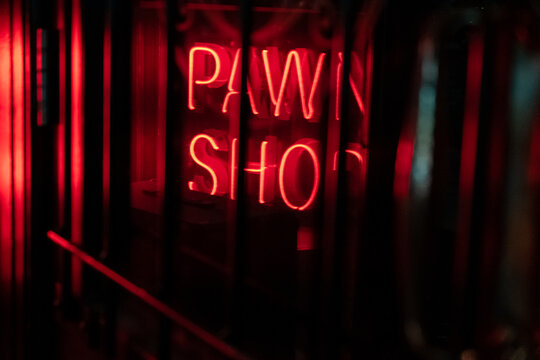 A Neon Sign Saying Pawn Shop Viewed Through The Window Of A Door