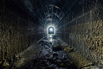 Dark and creepy old historical vaulted flooded underground drainage tunnel - obrazy, fototapety, plakaty