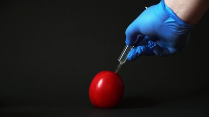 a man sticks a syringe with carcinogens in a tomato - Powered by Adobe