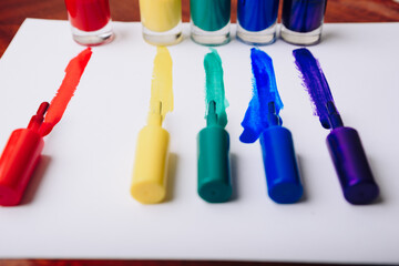 multi- colored nail polishes and traces of them on a white background