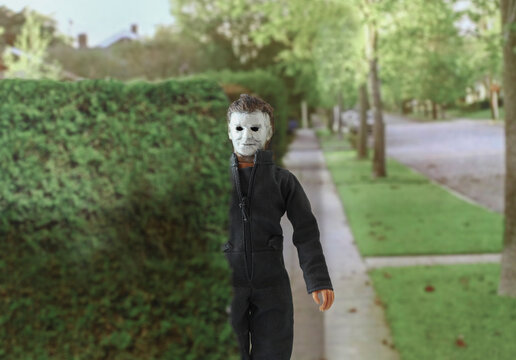 NEW YORK USA - JULY 23 2018: Recreation of a scene from the 1978 movie Halloween; Michael Myers (the shape) hiding behind a hedge as he stalks his victims in thfictional town of Haddonfield Illinois 
