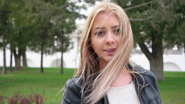 The young blonde is fixing her hair, which is trying to dishevel the wind.