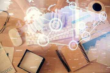 Double exposure of man's hands typing over computer keyboard and social network theme hologram drawing. Top view. People connection web concept.