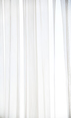White tulle curtain with vertical folds. Window with light curtains. Soft textile texture. Light...