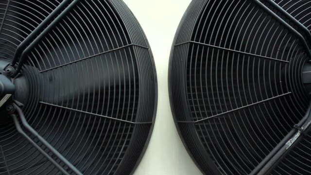 Two large industrial air conditioning condenser fans slowly rotating