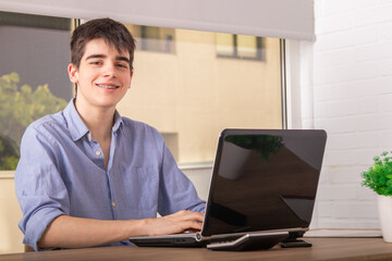 teenage student with computer at desk at home or college