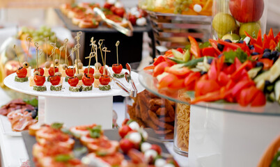 Catering. The table is richly richly filled with various snacks and vegetables. Focus on tomato and cheese snacks