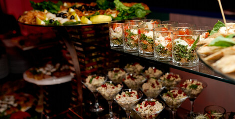 Catering. Glasses with salads and snacks on glass shelves. 