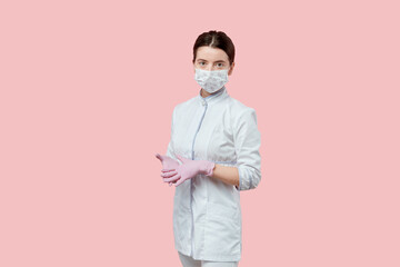 Cute brunette girl with gathered hair in a medical coat, gloves and mask.