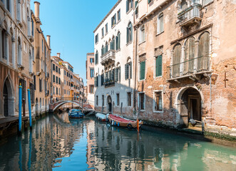 Fototapeta na wymiar Scenic View of Venetian Canal with Boats under Blue Sky in Venice, Italy