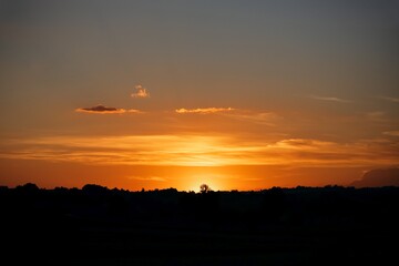 Orange sunset. Clouds over the contours of forest