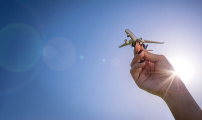 Travel background. White toy plane in girl hand flight in sunlight sky. Airplane, aircraft in bright sun light air fly concept.