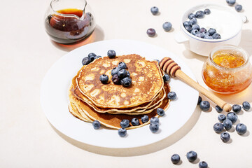 A stack of plain pancakes served with honey and blueberry