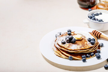 A stack of plain pancakes served with honey and blueberry