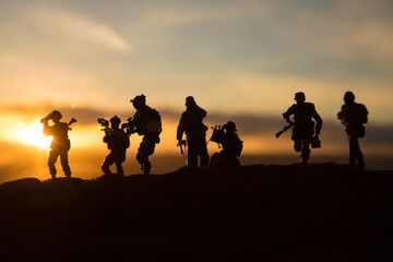Fototapeta na wymiar War Concept. Military silhouettes fighting scene on war fog sky background, World War Soldiers Silhouette Below Cloudy Skyline At sunset.