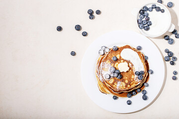A stack of plain pancakes served with honey and blueberry