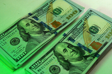 Close up view of a couple of 100 dollars bills bundle. Taken inside a softbox with soft white and green lights
