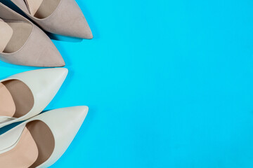 two pairs of female shoes to the left on a blue background with place for text, top view, close-up.