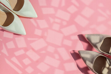 two pairs of women's shoes in the corners of the left and right on a pink background with a place for text in the middle, top view close-up.