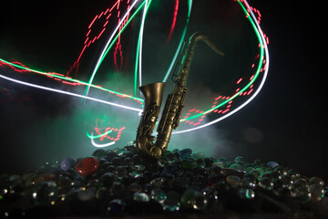 Alto gold sax miniature with colorful toned light on foggy background. Saxophone music instrument in lowlight. Selective focus