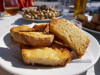 Sliced toasted bread with butter, with cooked snails in the background