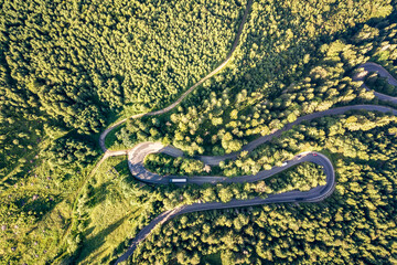 Aerial view of winding road in high mountain pass trough dense green pine woods.