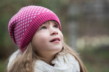 Pretty child girl in warm knitted winter clothes outdoors.