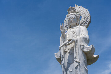 Fototapeta na wymiar Detail of Lady Buddha statue in a Buddhist temple and blue sky background in Danang, Vietnam. Closeup, copy space