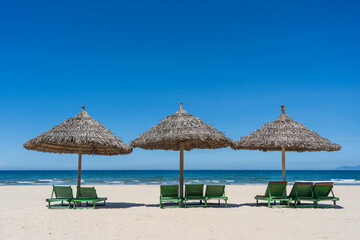 Tropical sand beach and summer sea water with blue sky and straw umbrella. Travel and nature concept
