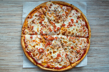 Tasty margarita pizza on baking paper on wooden table top view