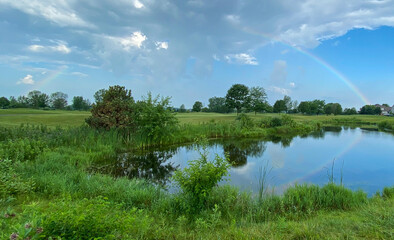 rainbow on golf course pond reflection