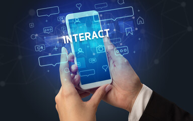 Female hand typing on smartphone with INTERACT inscription, social media concept