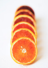 Close up of Sliced blood oranges ranging from light to dark on white background in a line