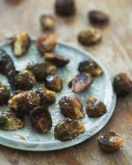 Roasted maple dijon brussell sprouts on ceramic plate on rustic wood table