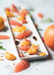 Citrus and dill salad plated on long white plate on white surface