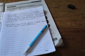 Mockup. Album pages, pencil for drawing on a table. The language of Bahasa Indonesia written on a paper