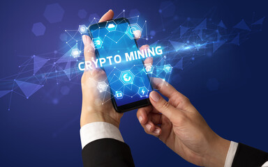 Female hand holding smartphone with CRYPTO MINING inscription, modern technology concept
