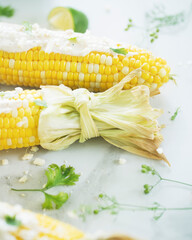 Corn on the cob with creamy sauce, lime, seasoning, and lime