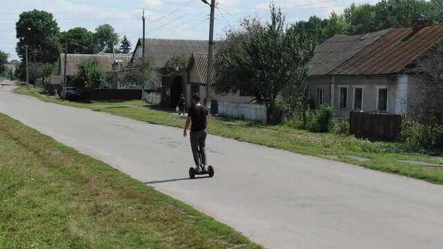 Man Riding Hoverboard Down a Road on a Sunny Summer Day